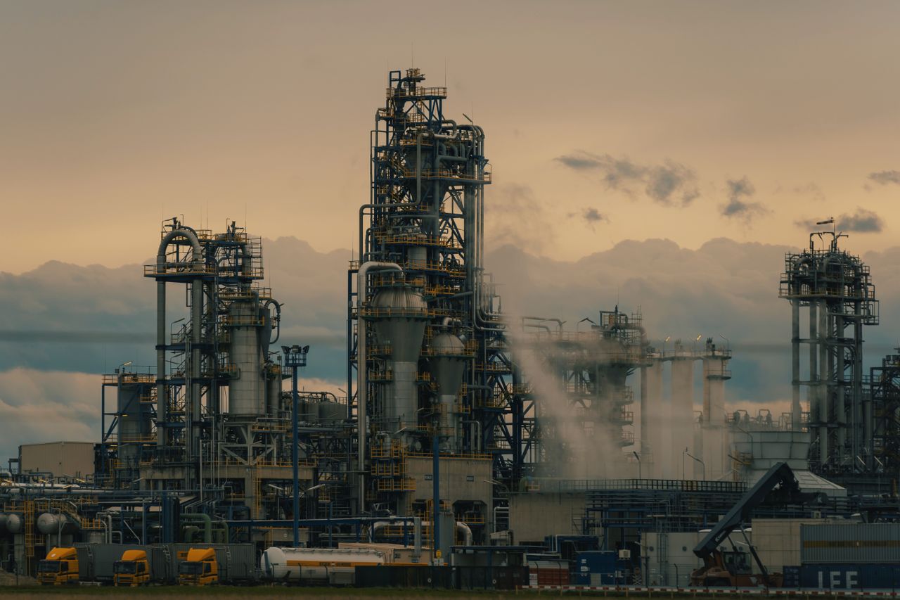 Oil refinery with distillation towers and tanker trucks at sunset