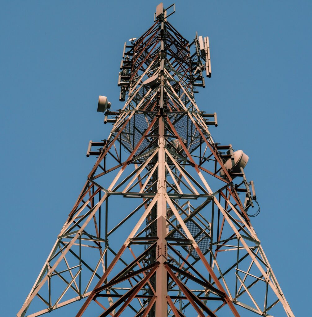 Cell tower with panel antennas and microwave dishes against a clear sky